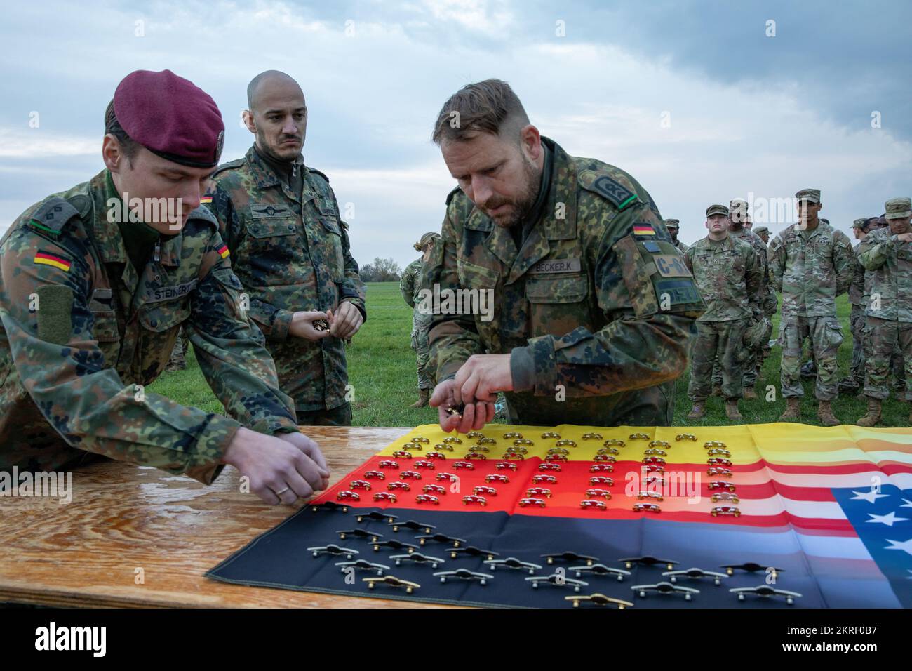 I jumpmasters tedeschi con la Brigata Airborne 26th raccolgono i distintivi paracadutisti tedeschi prima di fissarli in italiano e negli Stati Uniti Paracadutisti dell'esercito dopo aver condotto un'operazione aerea a Juliet Drop zone, Italia, 15 novembre 2022. I paracadutisti hanno tenuto una cerimonia dopo il completamento delle operazioni di salto e hanno scambiato i badge aerei appartenenti al loro paese. La Brigata Airborne 173rd è la U.S.A. Forza di risposta di contingenza dell'esercito in Europa, capace di proiettare le forze pronte dovunque negli Stati Uniti Aree di responsabilità dei comandi europei, africani o centrali. Foto Stock