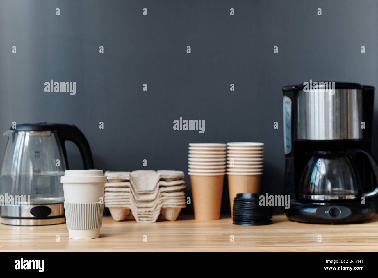 Primo piano della macchina per il caffè e della teiera con tazze ecologiche per preparare il caffè durante la pausa caffè in ufficio Foto Stock