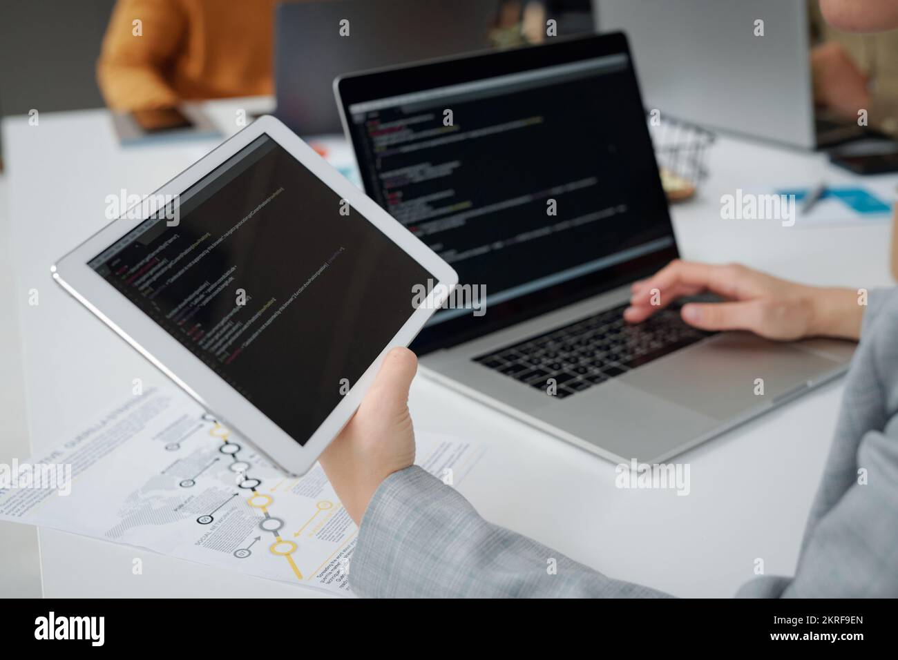 Primo piano del programmatore che lavora su computer e tablet digitale, scrive codici computer al tavolo dell'ufficio IT Foto Stock