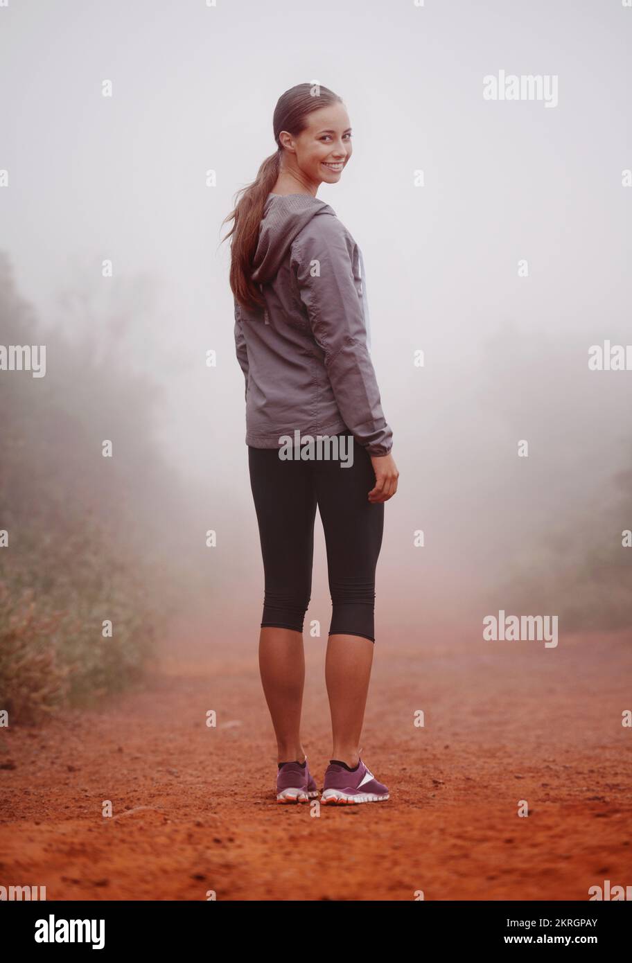 Non preoccuparti, non mi perderò nella nebbia. Una giovane donna in forma che si alza sulla spalla mentre si trova su un percorso all'aperto. Foto Stock