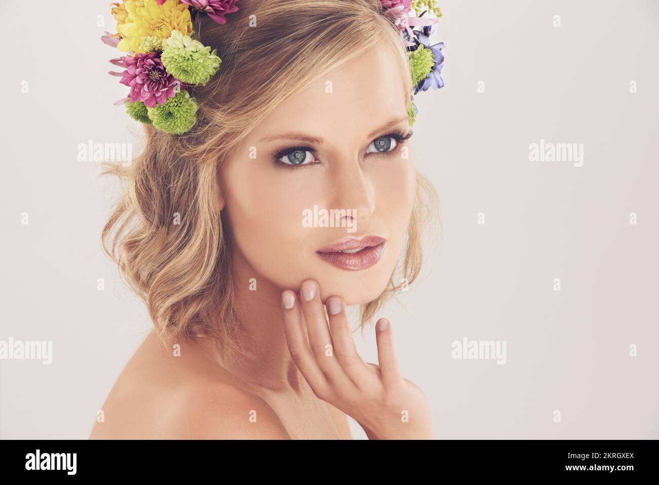La sua bellezza è naturale come sono... Studio girato di una bella giovane donna con fiori nei suoi capelli. Foto Stock
