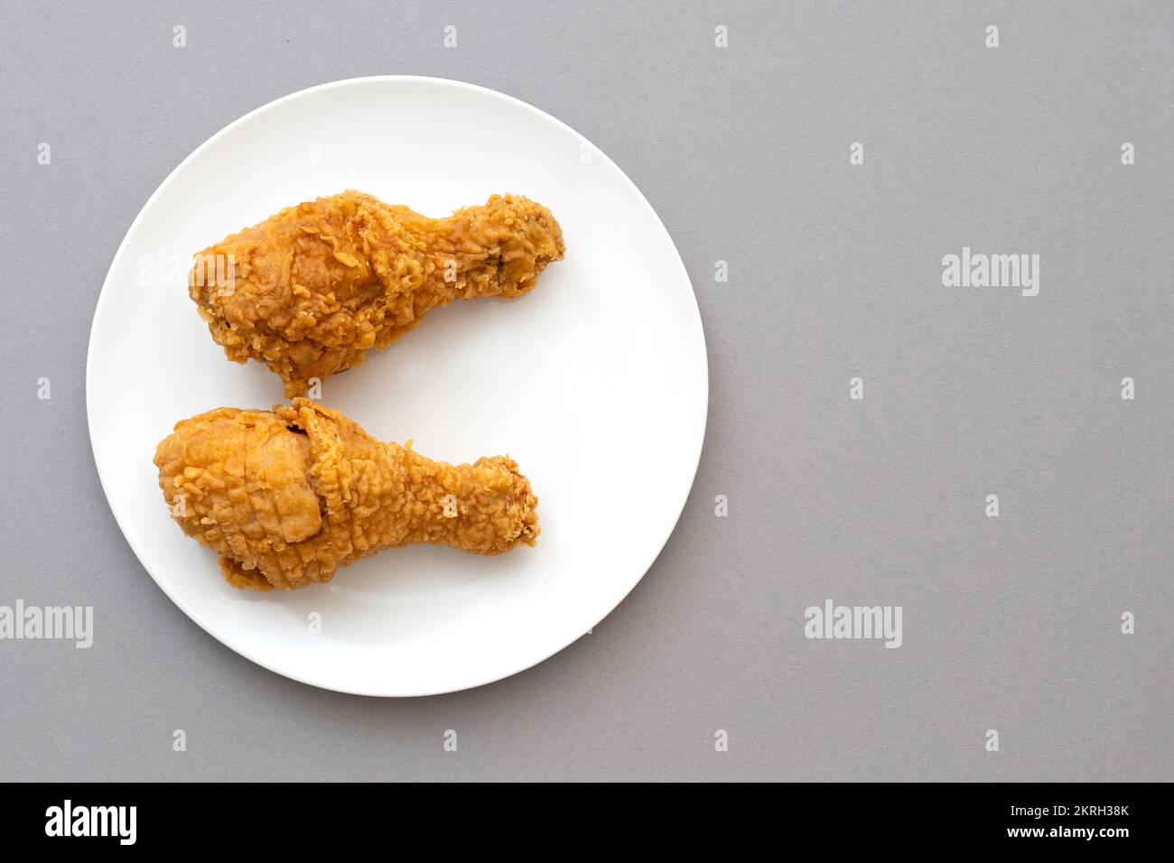 Due cosce di pollo fritte tostate o bastoncino di pollo su un piatto di ceramica bianca, vista dall'alto Foto Stock