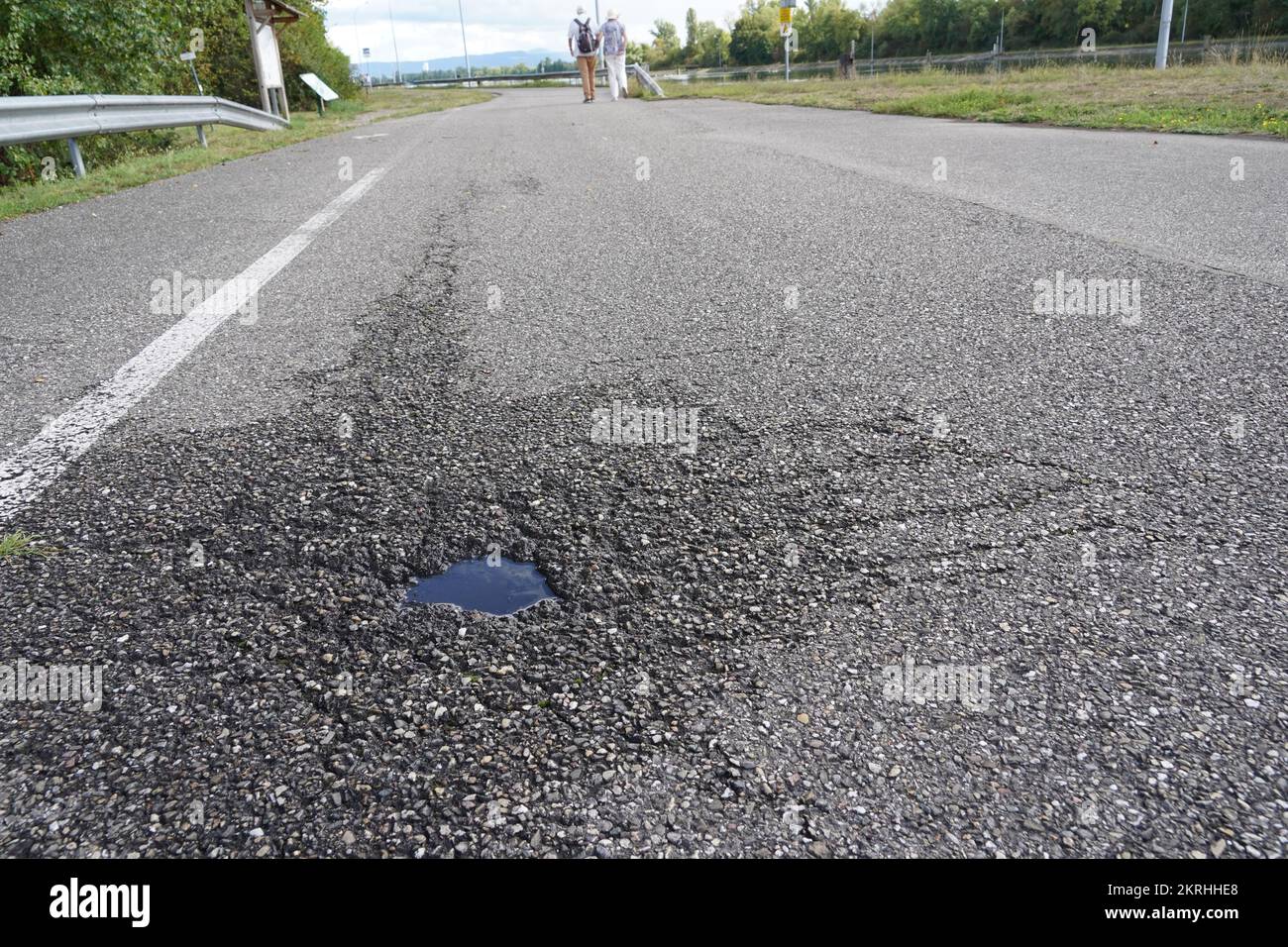 Strada asfaltata con un piccolo buche pieno di acqua piovana in vista ad angolo basso. Foto Stock