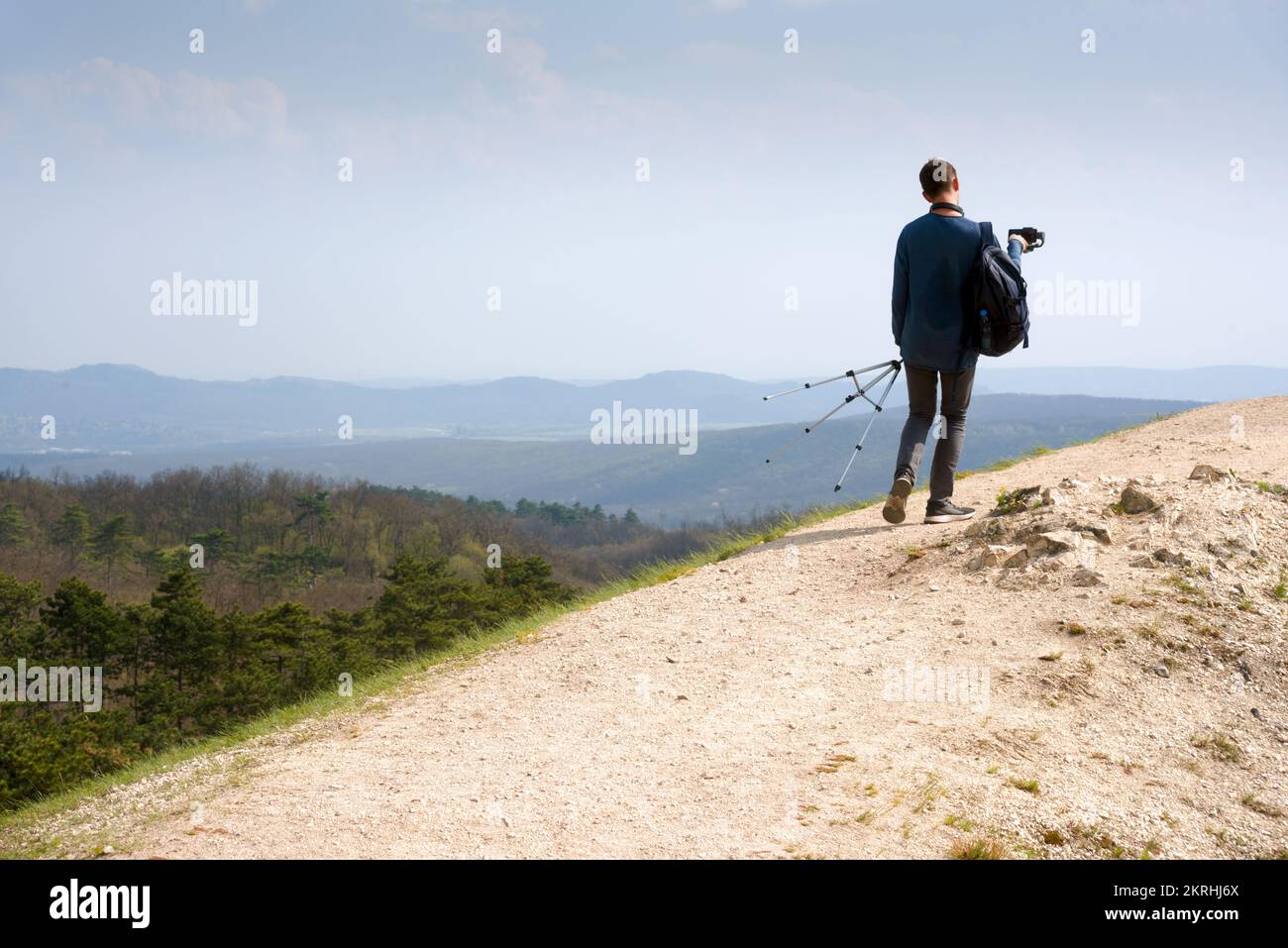 Giovane uomo che cammina con il cavalletto in montagna Foto Stock