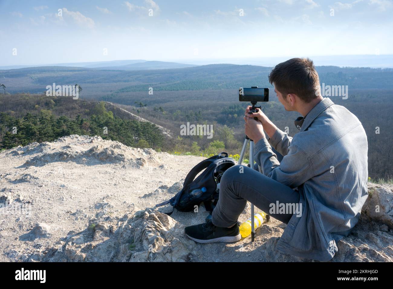 Fotografo che fotografa in montagna utilizzando il telefono cellulare e il cavalletto Foto Stock
