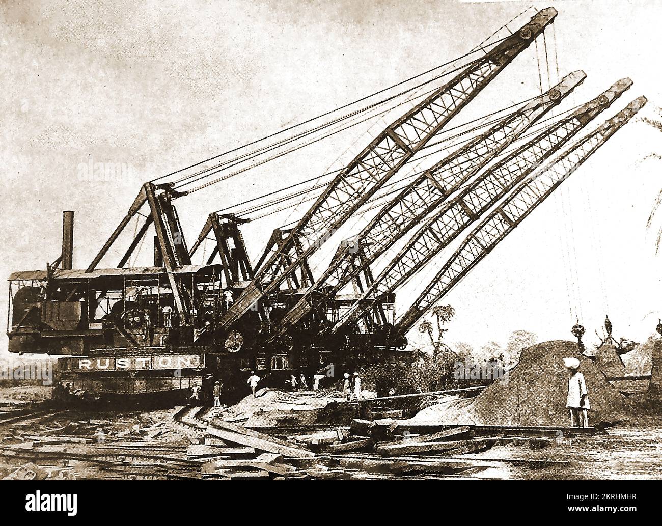 Scavare canali in India negli anni '30 utilizzando gru a linea di trascinamento, ciascuna in grado di un cucchiaio da dieci tonnellate. Il dragline è stato inventato nel 1904 da John W. Page per scavare il canale di Chicago --- 1930 के दशक में ड्रैग-लाइन क्रेन का उपयोग करके भारत में नहरों की खुदाई, जिनमें से प्रत्येक दस टन बाल्टी स्कूप में सक्षम था। ड्रैगलाइन का आविष्कार 1904 में जॉन डब्ल्यू पेज ने शिकागो नहर खोदने के लिए किया था - ۱۹۳۰ کی دہائی میں ڈریگ لائن کرین کا استعمال کرتے ہوئے ہندوستان میں نہروں کی کھدائی کی گئی، جن میں سے ہر ایک دس ٹن بالٹی اسکوپ کرنے کی صلاحیت رکھتی ہے۔ Foto Stock