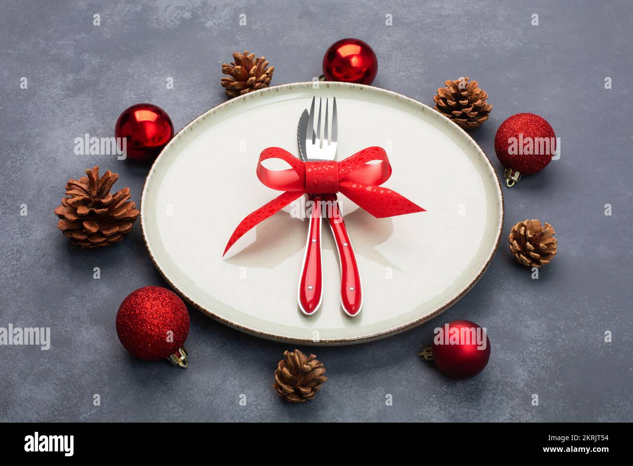 Tavolo di Natale composto da un piatto e posate legate con un arco e decorazioni natalizie Foto Stock