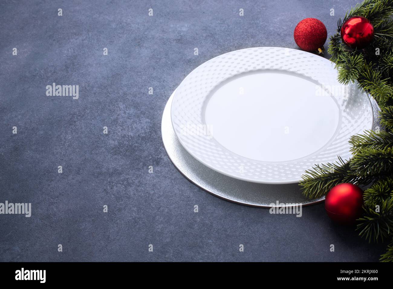 Tavolo di Natale composto da un piatto bianco vuoto e posate legate con un arco. Vista dall'alto con spazio di copia su sfondo blu Foto Stock