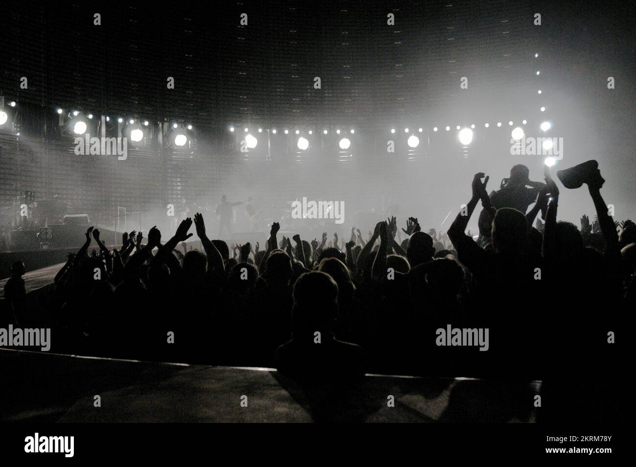 FOLLA SILHOUETTE, ATMOSFERA, U2 VERTIGO WORLD TOUR, 2005: La folla di 64.000 persone si fa selvaggia per gli U2 mentre le luci si spengono all'inizio del concerto al Millennium Stadium di Cardiff, giugno 29 2005. Fotografia: ROB WATKINS INFO: The U2 Vertigo Tour, dal 2005 al 2006, ha promosso il loro album "How to Dismantle an Atomic Bomb". Conosciuto per le sue performance ad alta energia e l'elaborato design scenico, il tour è stato un successo globale, mostrando successi come "Vertigo" e rafforzando lo status degli U2 come leggende del rock. Foto Stock