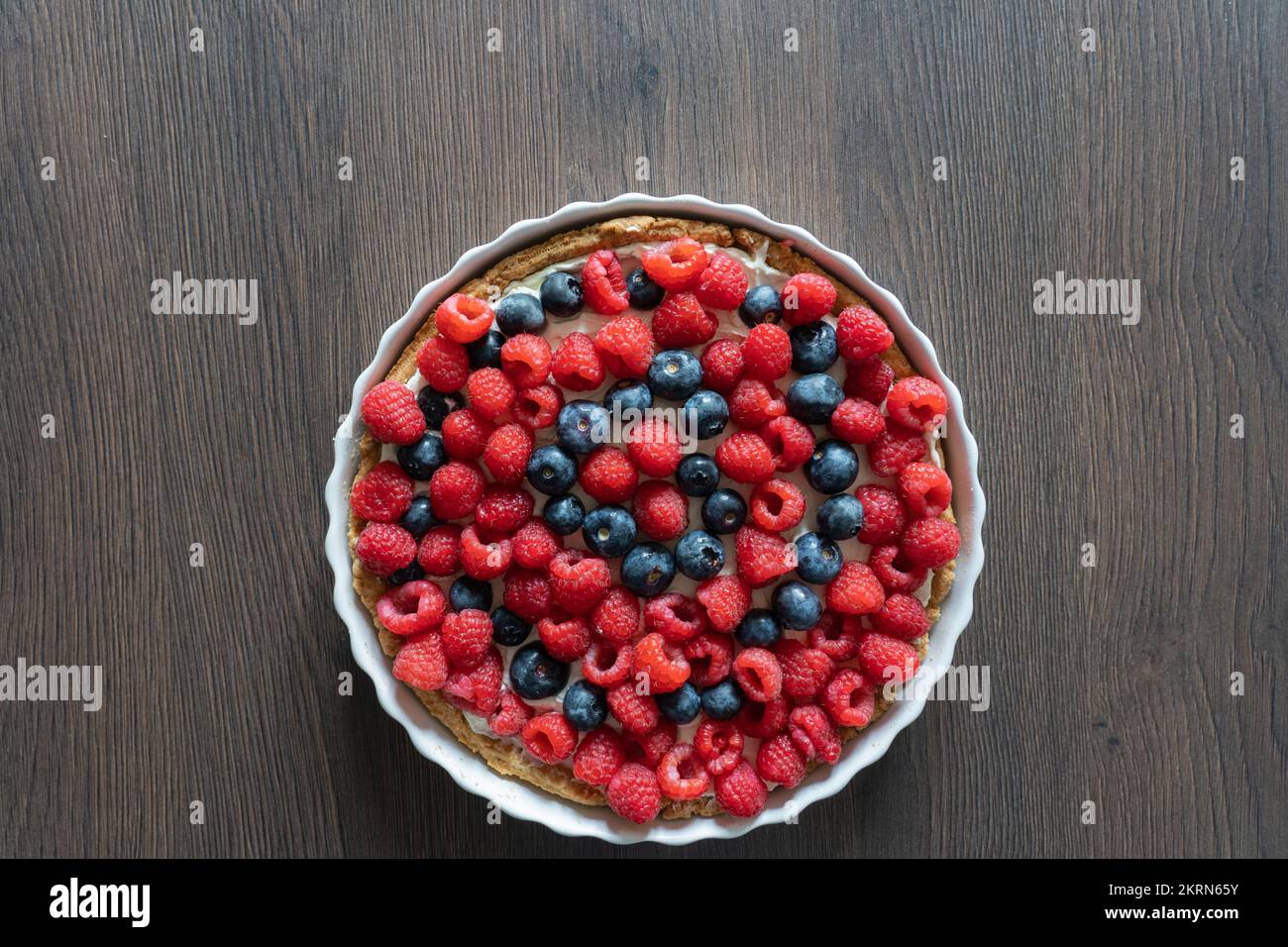 Delizioso dessert di pasta frolla di frutta mista al mirtillo e lampone fatto in casa in un piatto di ceramica bianca su un piano di lavoro da cucina Foto Stock