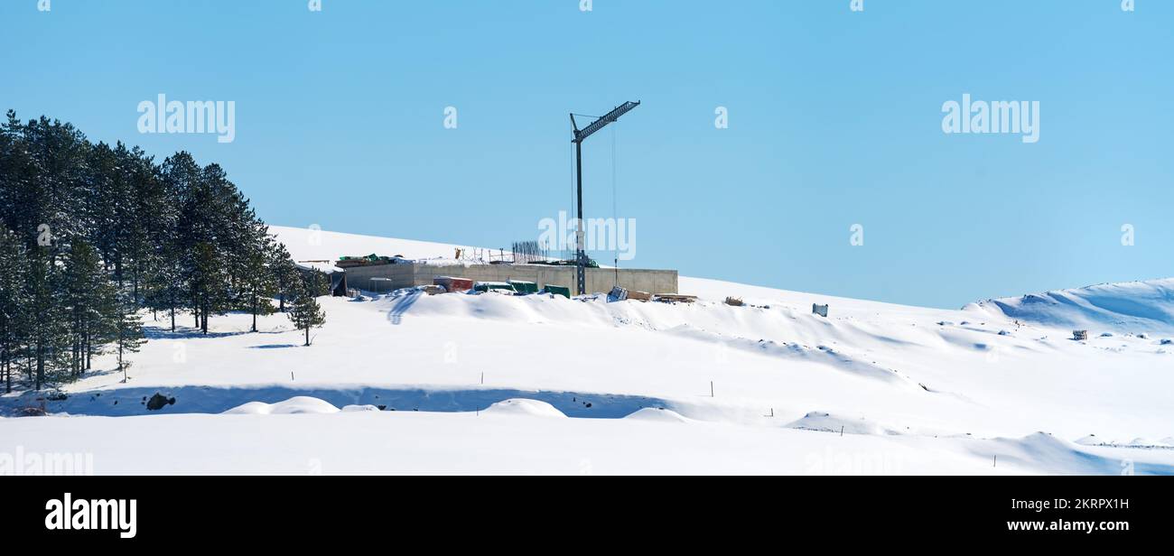 Cantiere edile e gru su una collina innevata in inverno al monte Zlatibor in Serbia Foto Stock