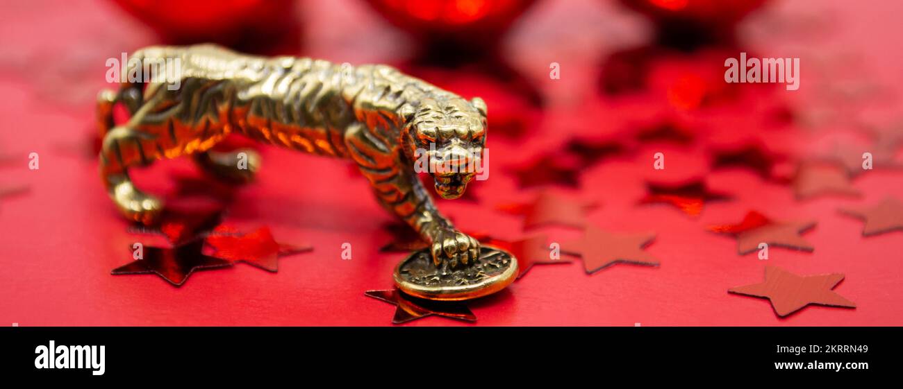 Banner con una figura in bronzo di una tigre con una moneta su sfondo rosso e stelle rosse, copia spazio. Foto Stock