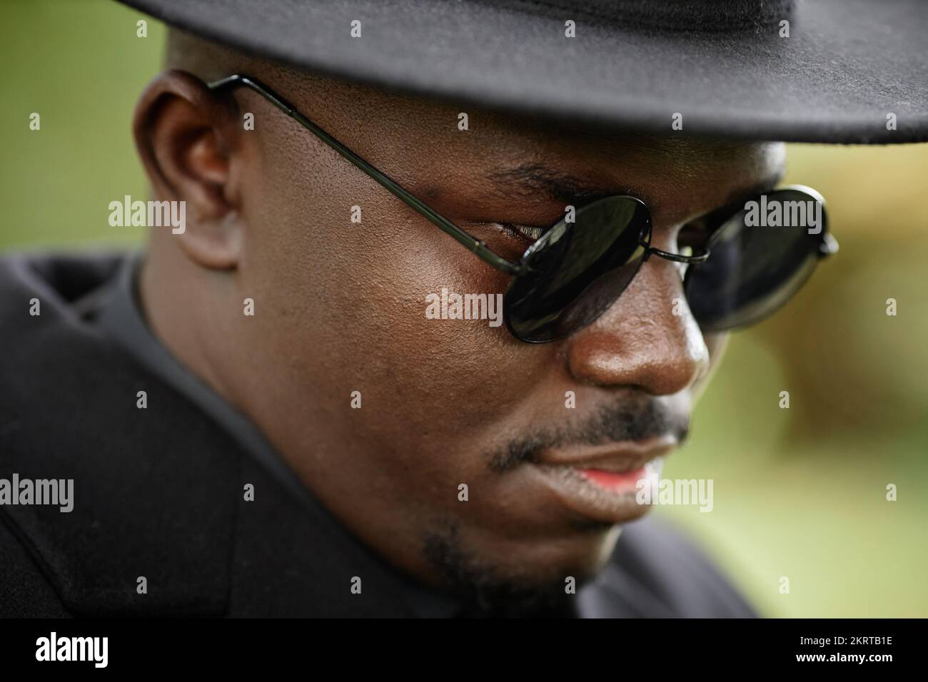 Primo piano di un uomo afro-americano che indossa un cappello nero con occhiali da sole Foto Stock