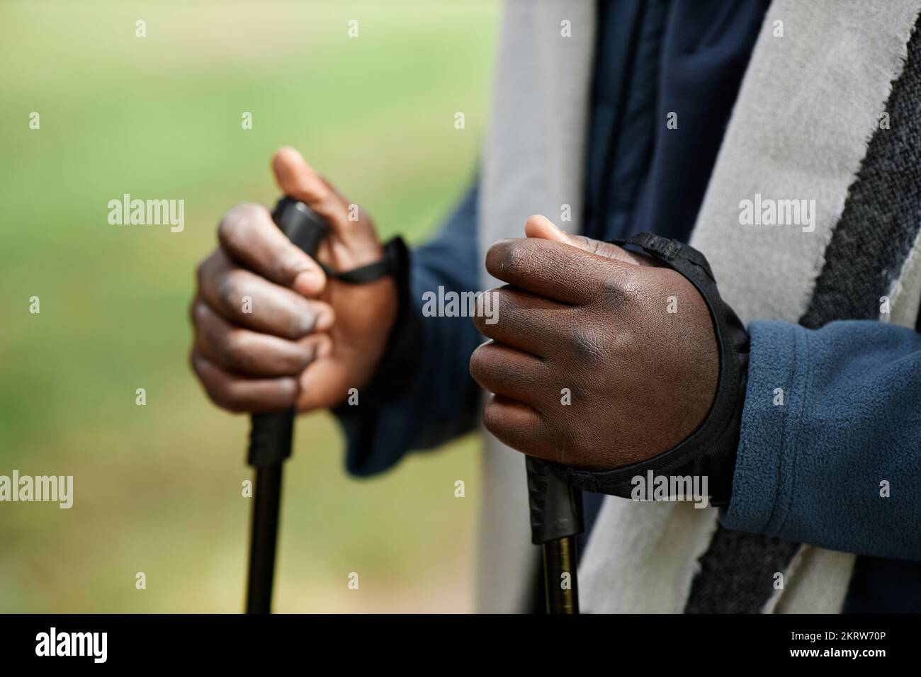 Primo piano delle mani maschili che tengono i pali da camminata durante l'escursione in natura Foto Stock