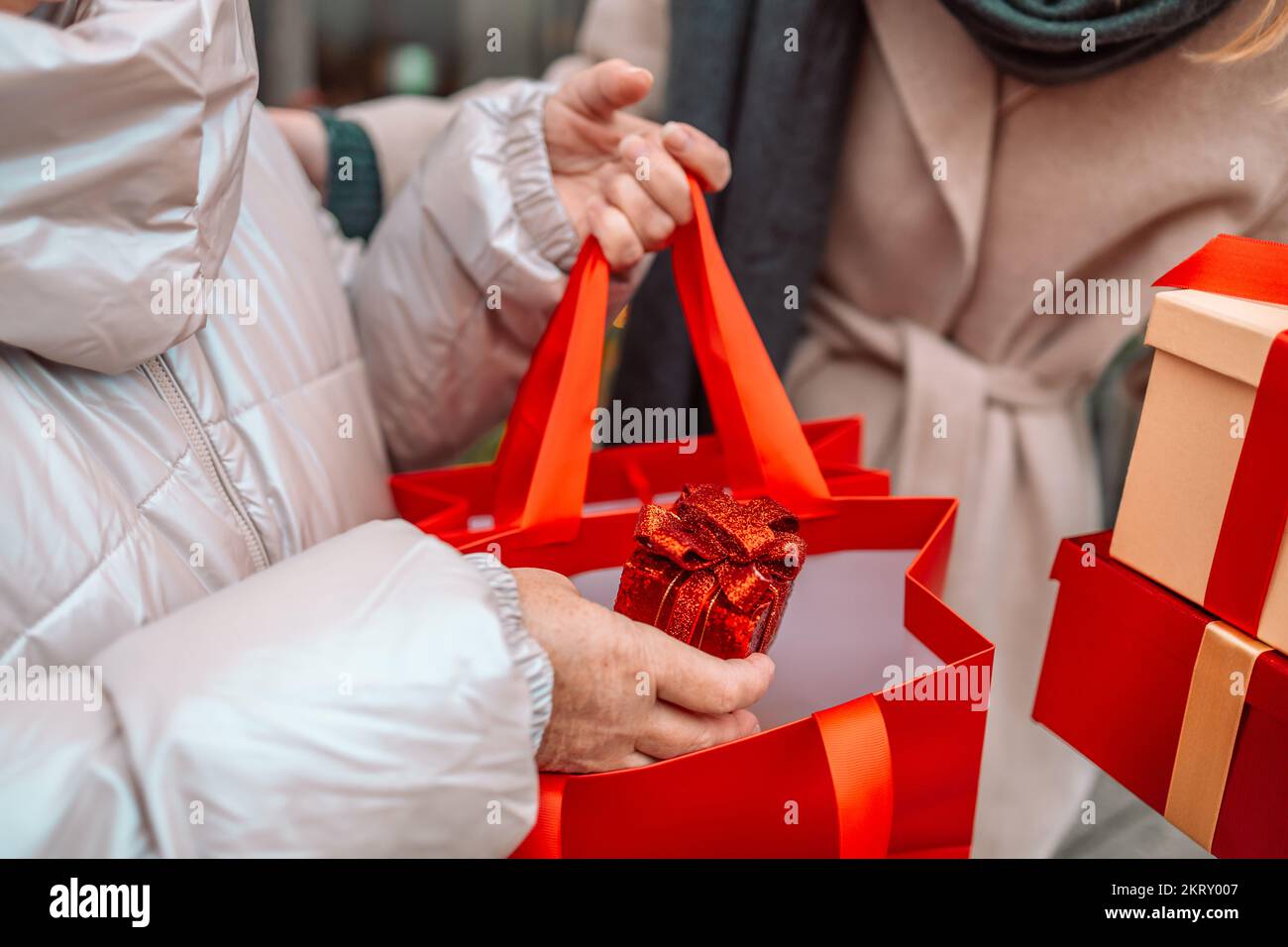 Due donne allegre stanno divertendosi nella strada della città a Natale, ridendo e comprando regali per i loro cari. Consumismo, shopping Foto Stock