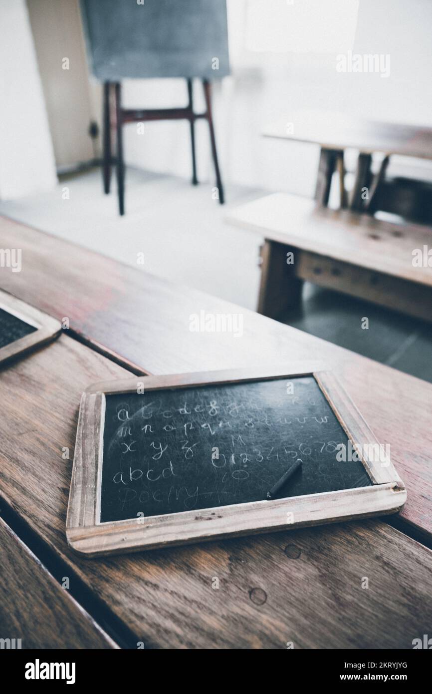 Un vecchio stile bambini ardesia tablet con stilo di scrittura in una scuola. Foto Stock