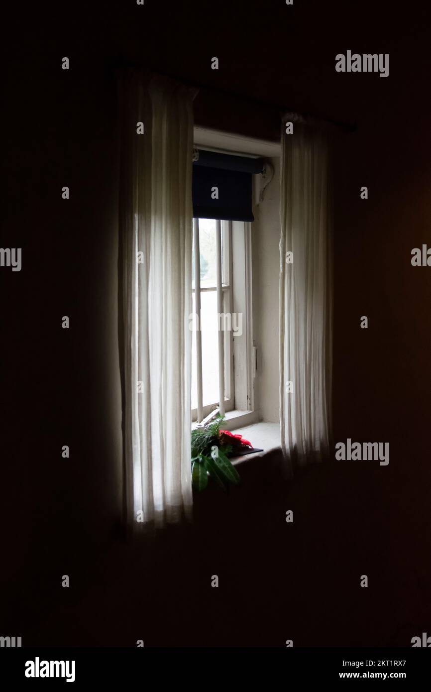 Luce inquietante in una finestra del cottage Foto Stock