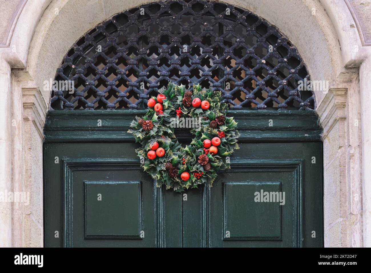 Tradizionale corona di Natale verde e rosso appeso alla porta d'ingresso della casa Foto Stock