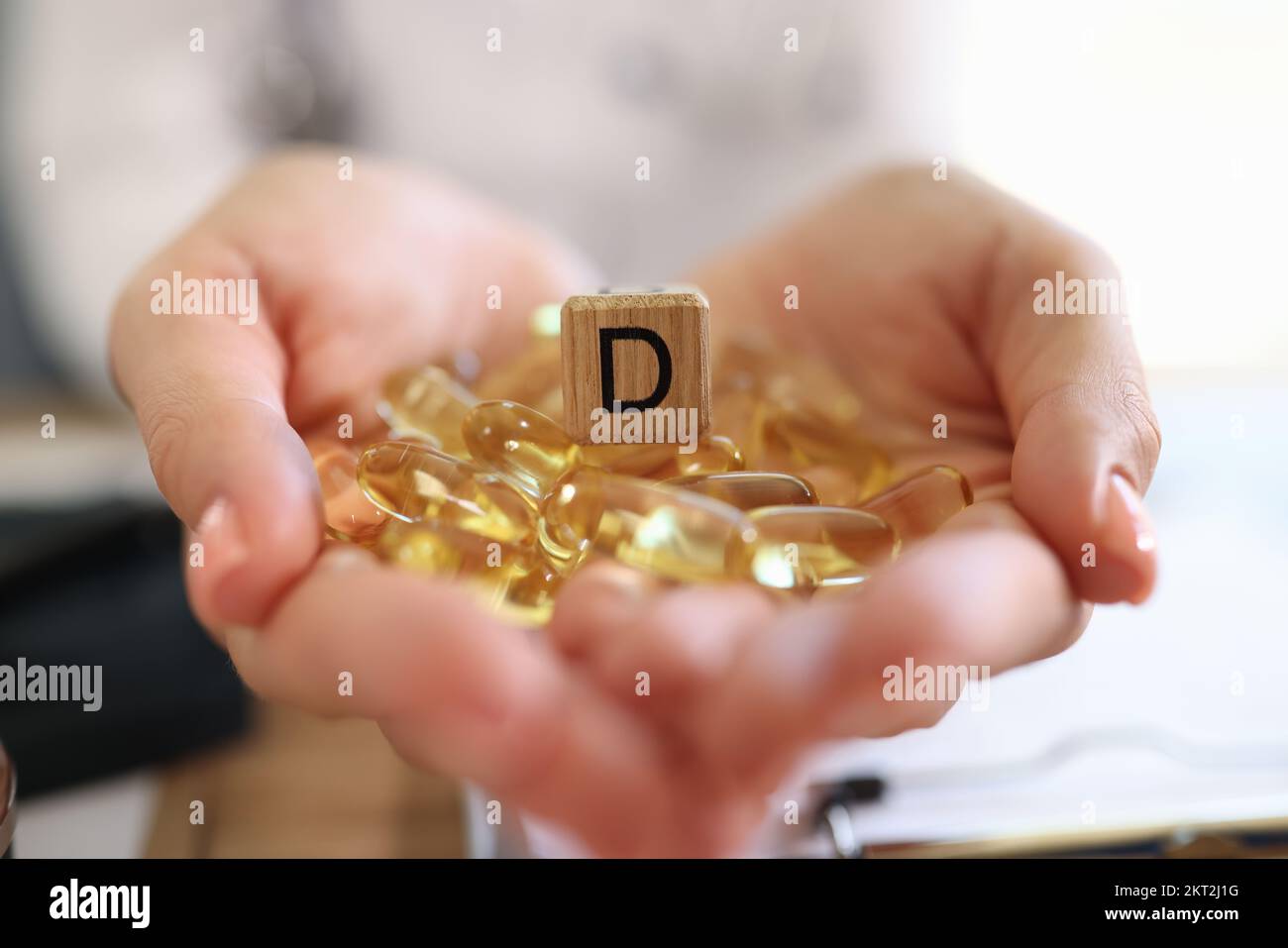 Primo piano delle mani di una donna che tiene molte capsule di vitamina D. Foto Stock