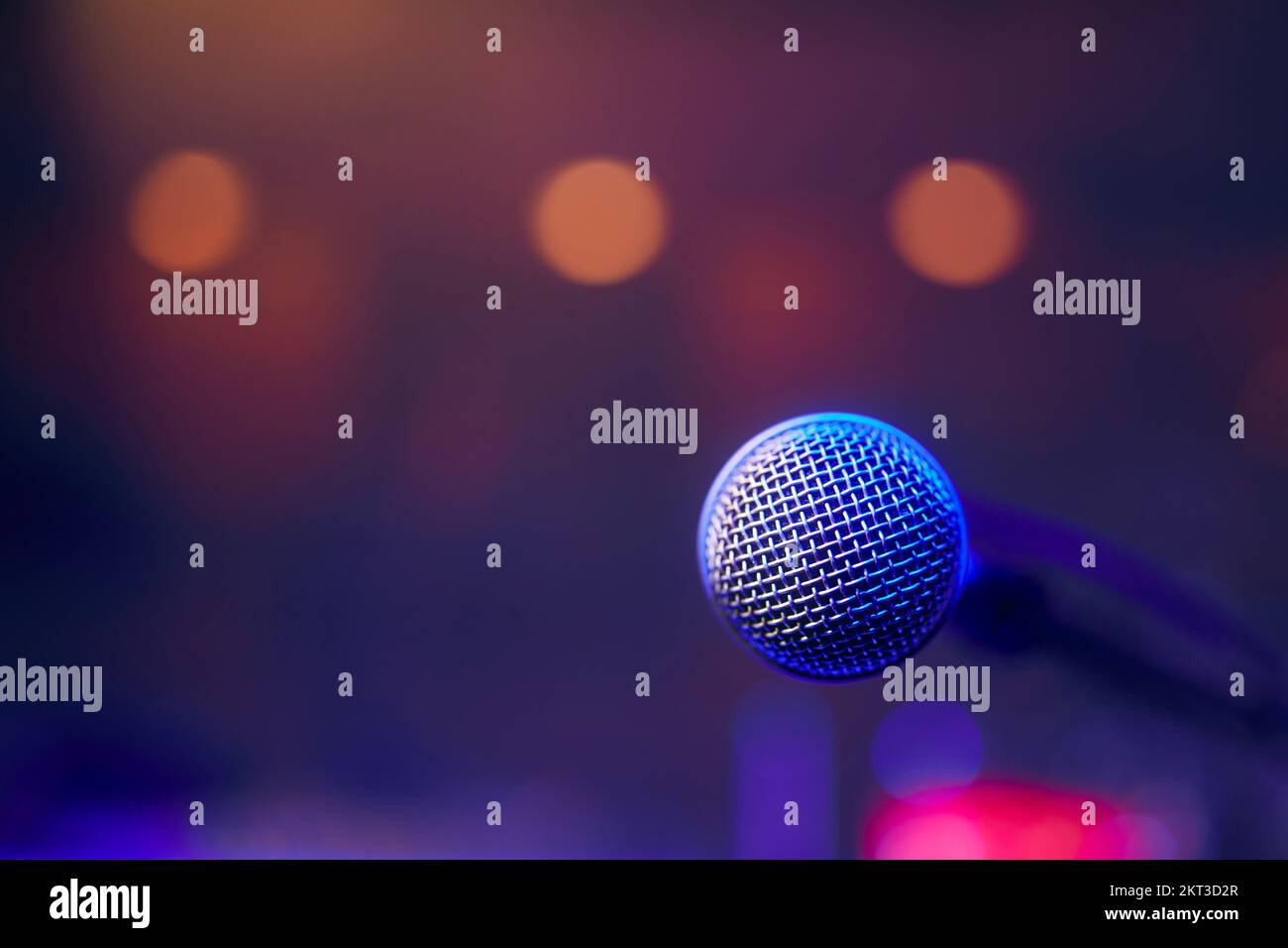Primo piano del microfono illuminato sul palco contro i faretti. Foto Stock