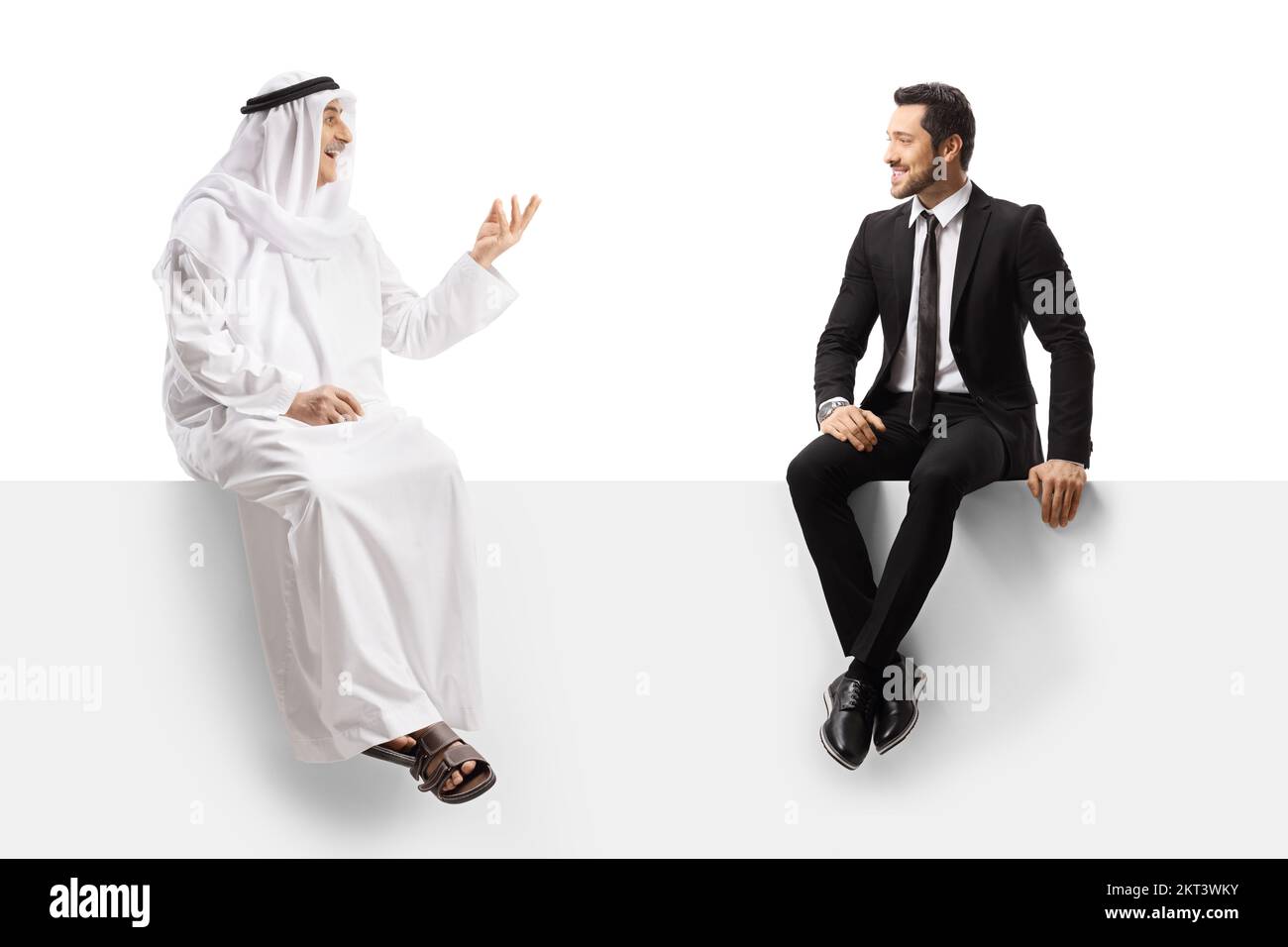 Uomo arabo in abiti etnici che parla con un uomo d'affari seduto su un pannello bianco isolato su sfondo bianco Foto Stock
