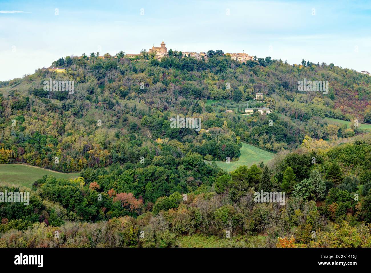 Vista autunnale di campi e boschi sotto Belvedere Fogliense, Regione Marche d'Italia. Sullo sfondo appare la città medievale di Mondaino Foto Stock