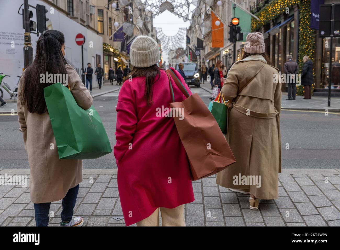 Gli amanti dello shopping natalizio nel centro di Londra con colorati cappotti invernali e borse per lo shopping a Piccadilly, nel centro di Londra, Inghilterra, Regno Unito Foto Stock