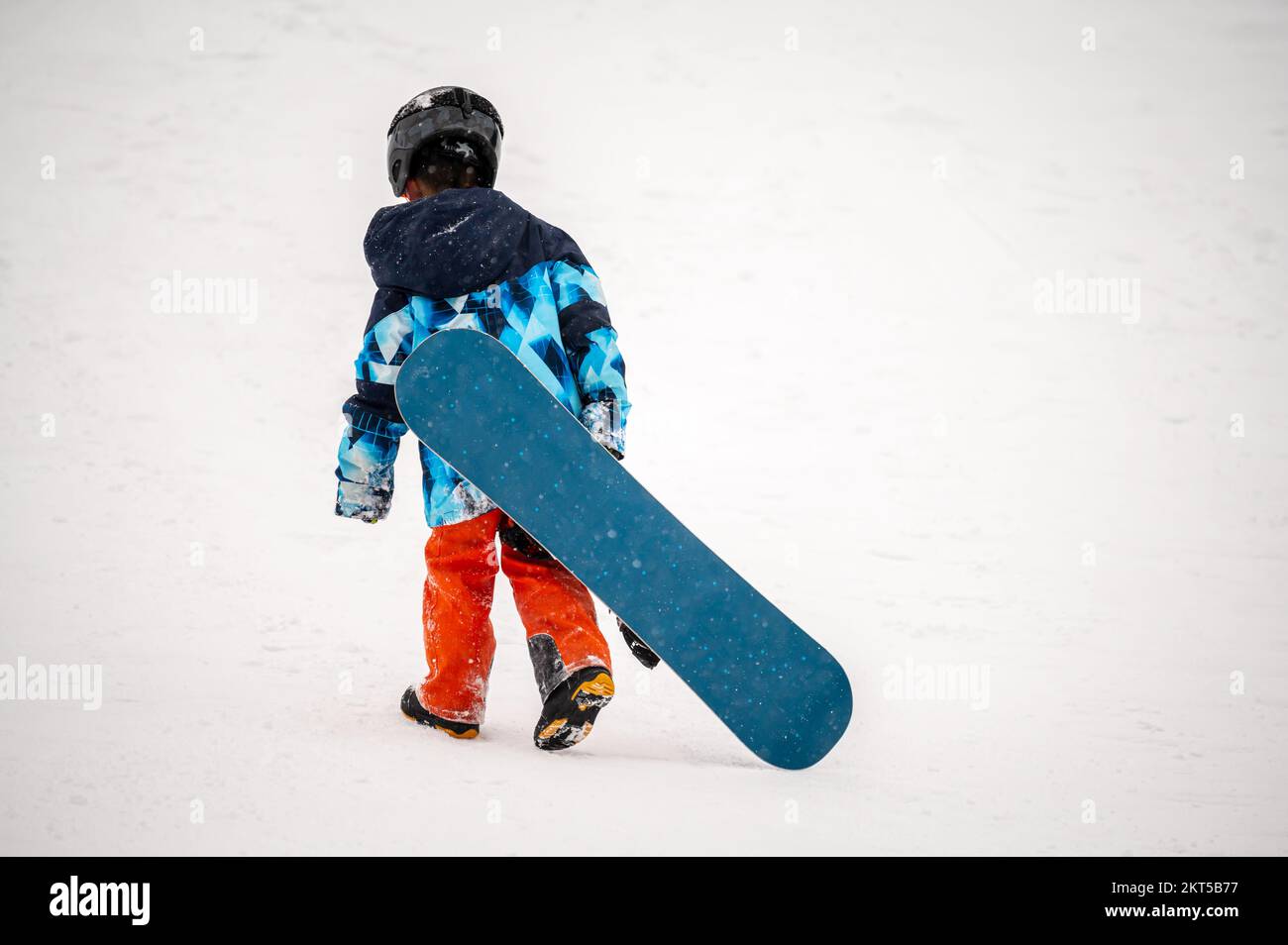 Persona con snowboard sulla neve. Un bambino asiatico cammina in inverno. Vacanze in Svizzera. Buona infanzia. Foto Stock
