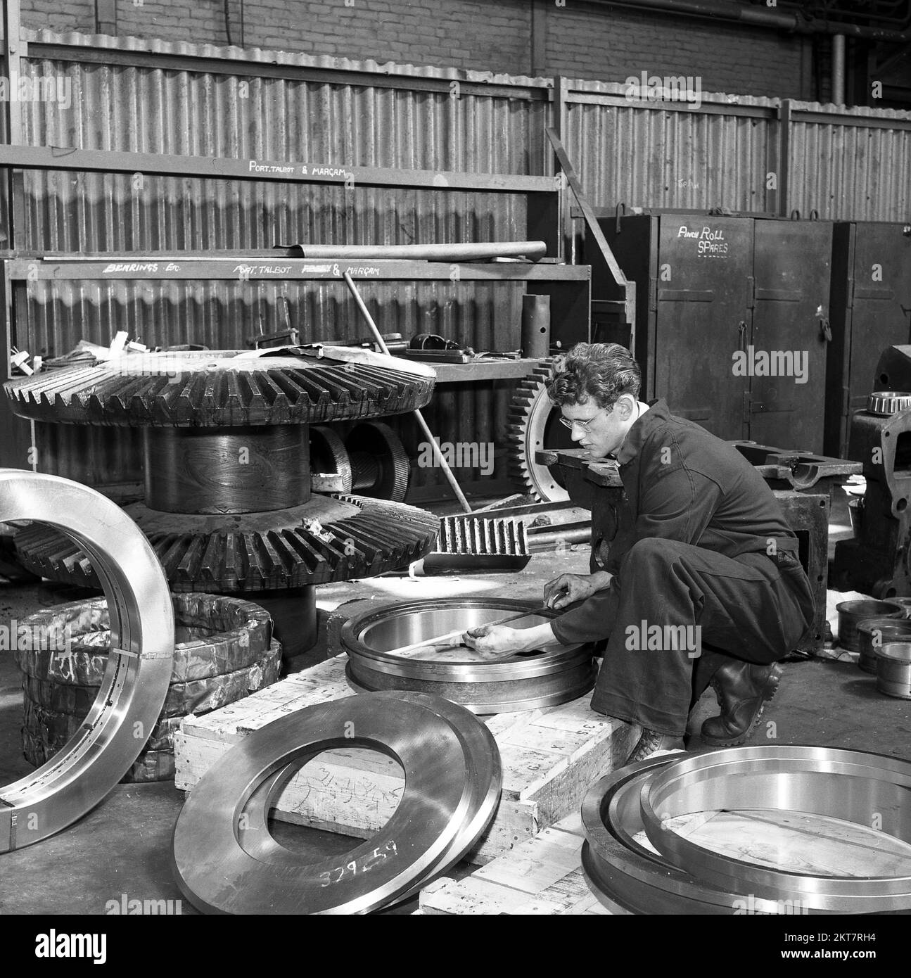 1950s, storico, acciaieria, giovane lavoratore maschile che misura cuscinetti in acciaio di nuova produzione, anelli, Port Talbot, Galles del Sud, Regno Unito. Steel Company of Wales LTS, Abbey Works Foto Stock