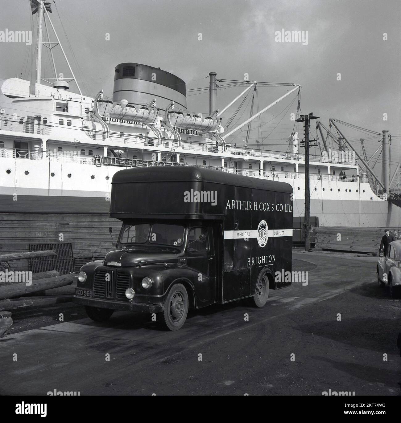 1950s, storico, Austin camion di consegna di fornitori chimici, Arthur H. Cox & Co Ltd, presso il porto di Londra, Inghilterra, Regno Unito. Nave a vapore dell'epoca, Drina ormeggiata. Foto Stock