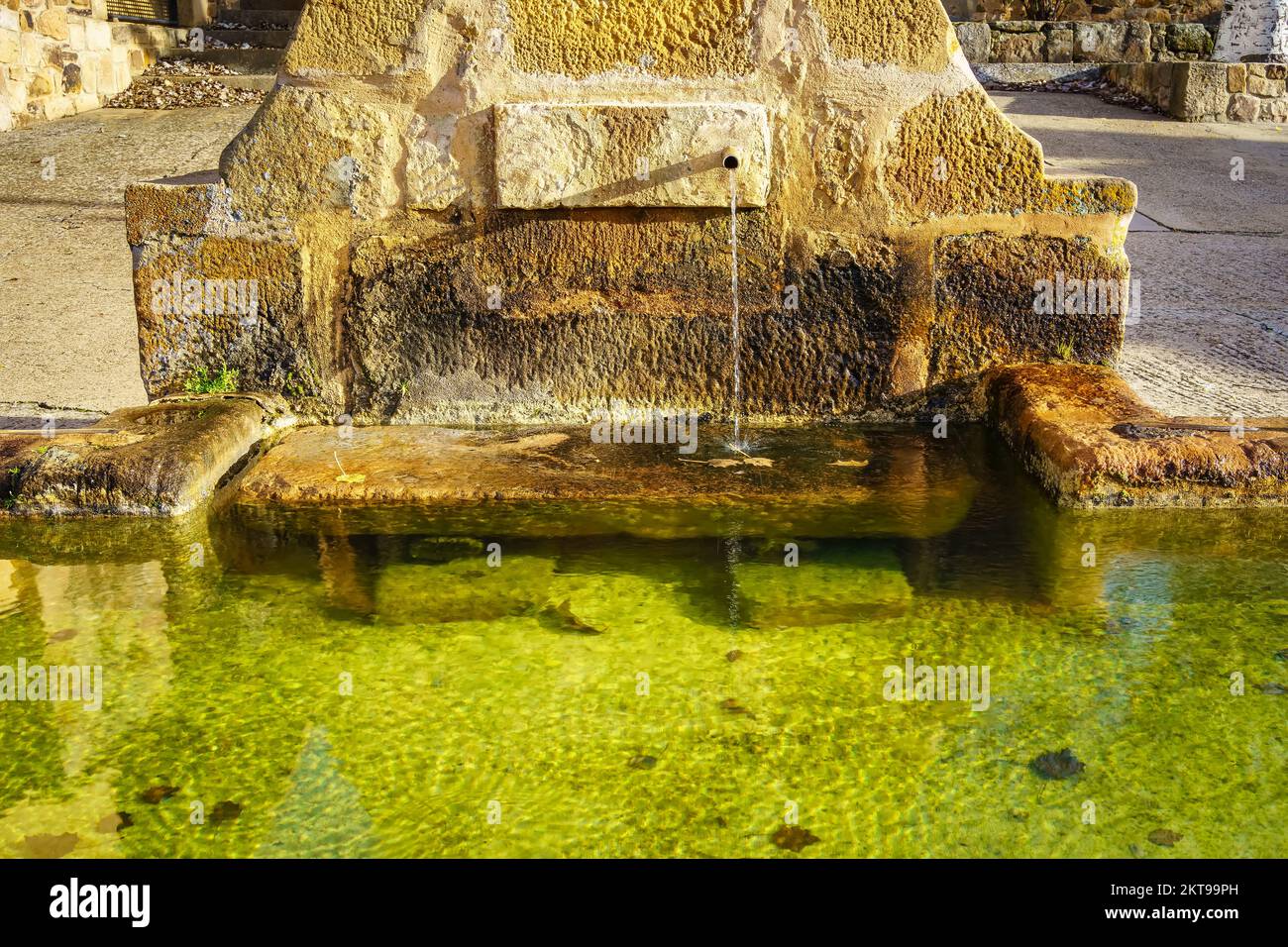 Antica fonte di acqua fresca e trasparente fatta di pietra in un vecchio villaggio in Spagna. Foto Stock