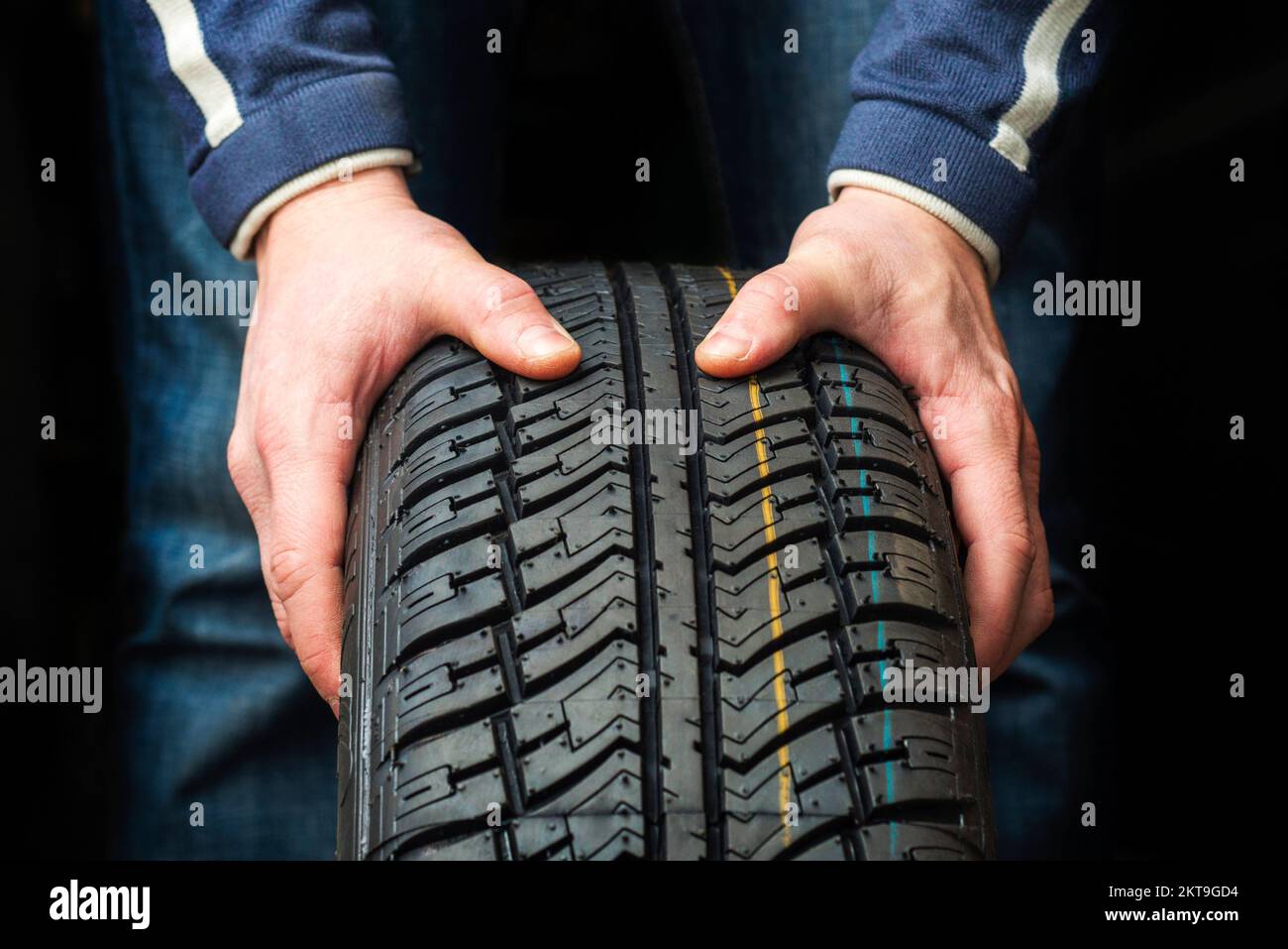 Primo piano di mani meccaniche che tengono uno pneumatico su sfondo scuro Foto Stock