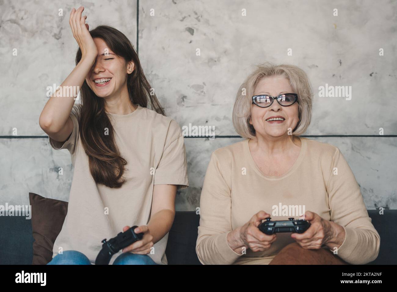 Ritratto di due pazze donne che si divertiscono a giocare a videogame su playstation indoor, tenendo in mano il gamepad per console. Vista frontale verticale. Stile di vita delle persone Foto Stock