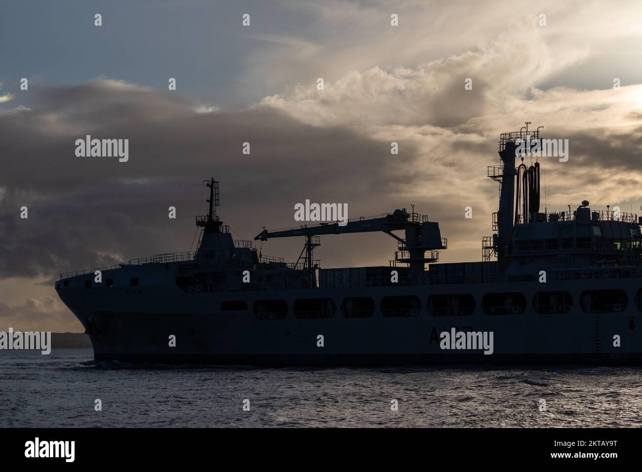 RFA Tiderace A137 che si muove nel punto stretto del porto di Portsmouth e si stagliò contro il sole tramontato. Foto Stock