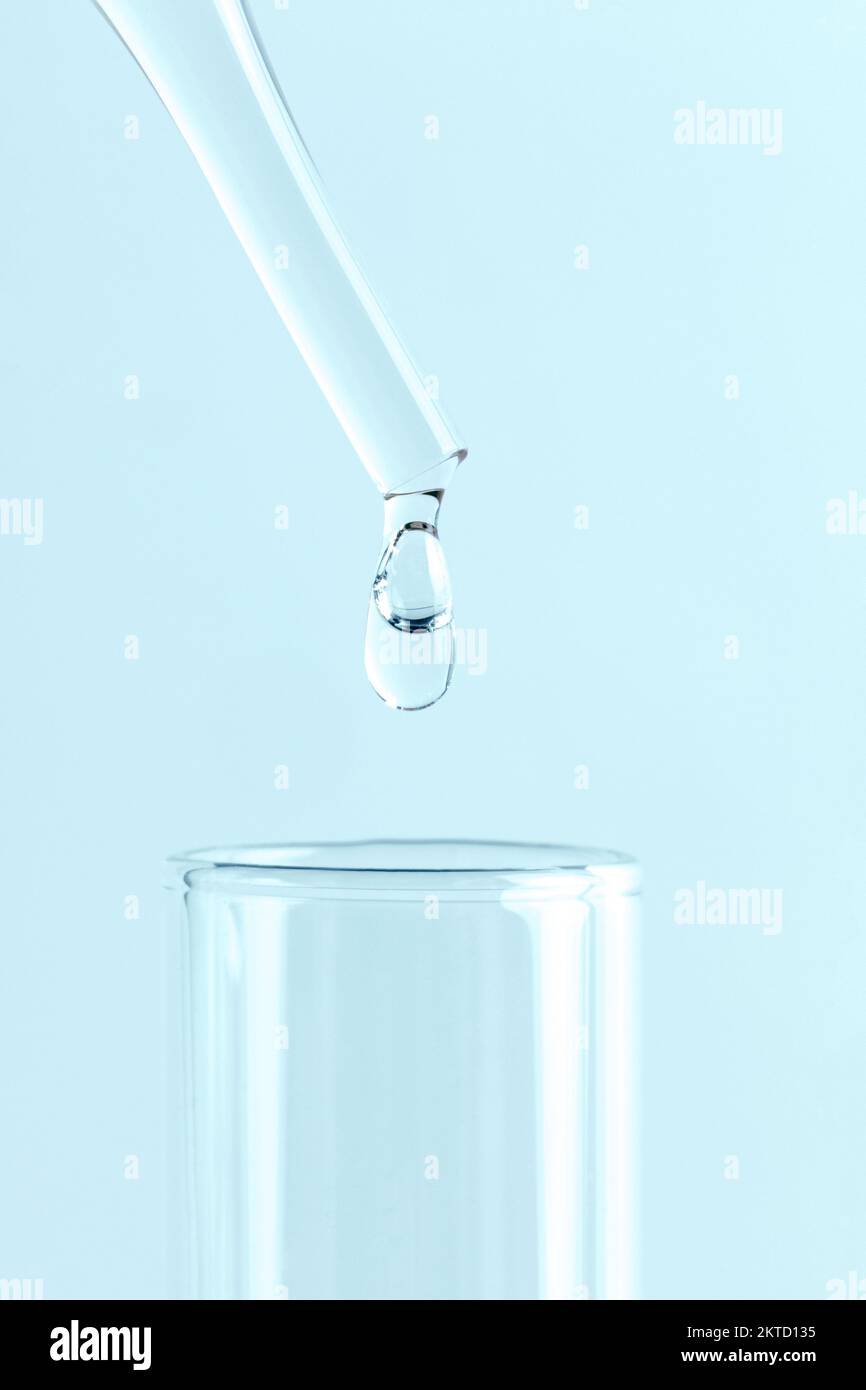 Primo piano di una pipetta in vetro da laboratorio con goccia di liquido su fondo bianco. Concetto di laboratorio medico o scientifico. Foto Stock