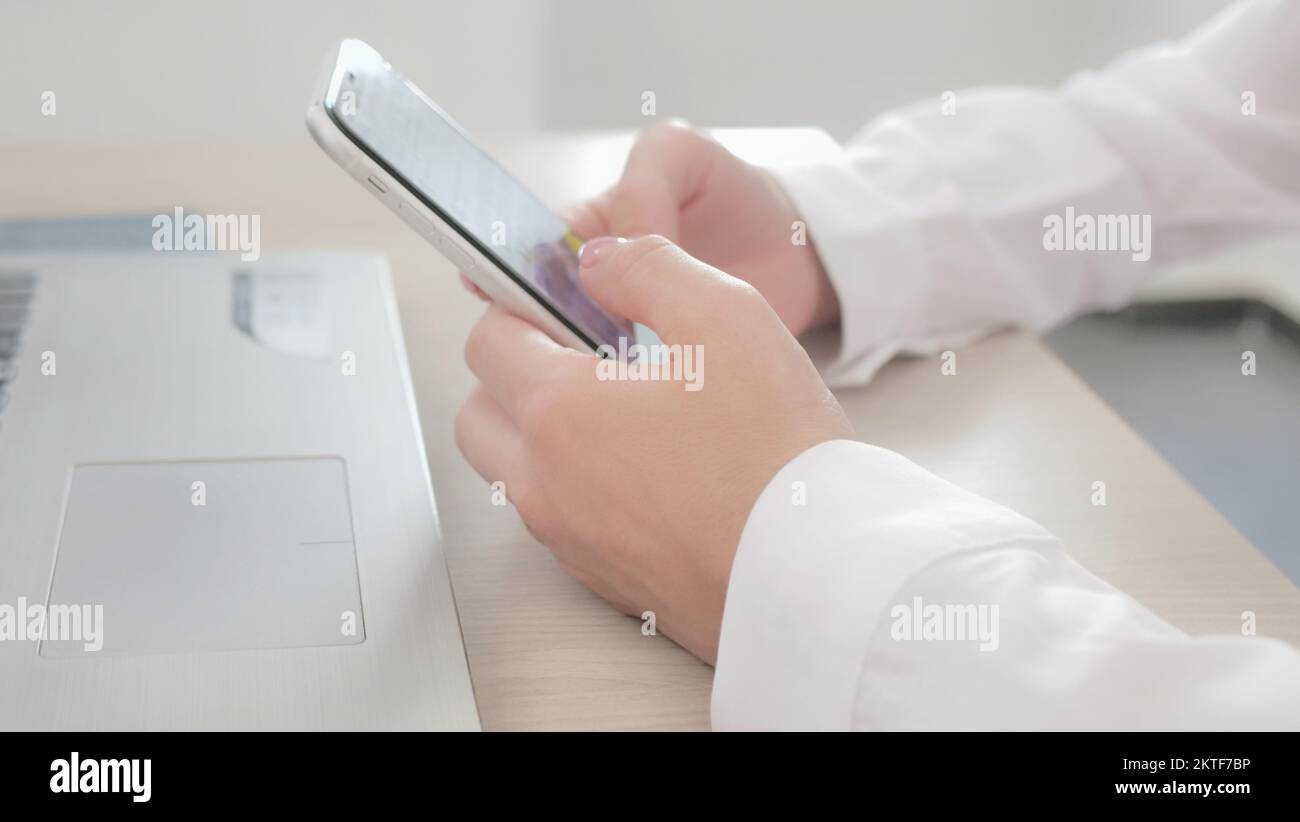 sul luogo di lavoro utilizzando lo smartphone, inviare messaggi, scegliere e acquistare beni e servizi online, concetto di utilizzo della tecnologia moderna. Primo piano della presa delle mani femminili Foto Stock