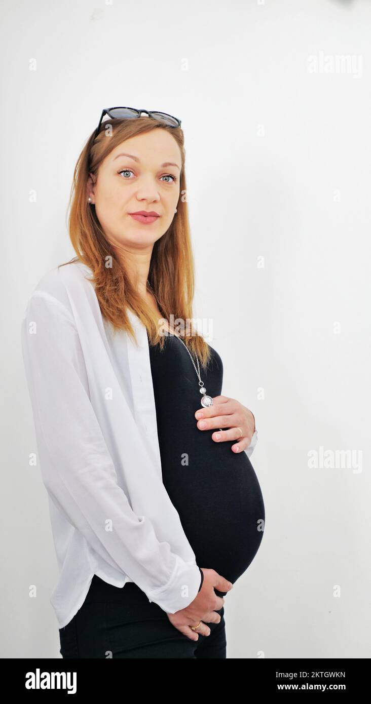 Una giovane donna incinta tiene le mani sul ventre gonfio. Concetto di amore, orizzontale con spazio di copia Foto Stock