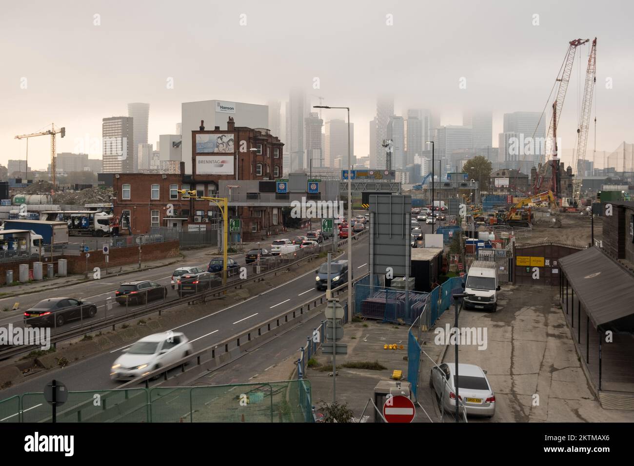 Nebbia, skyline dell'Isola di Dogs in lontananza, punto di vista dalla strada di avvicinamento Sud del Tunnel Blackwall, con traffico intenso, Greenwich, Londra Sud. Foto Stock