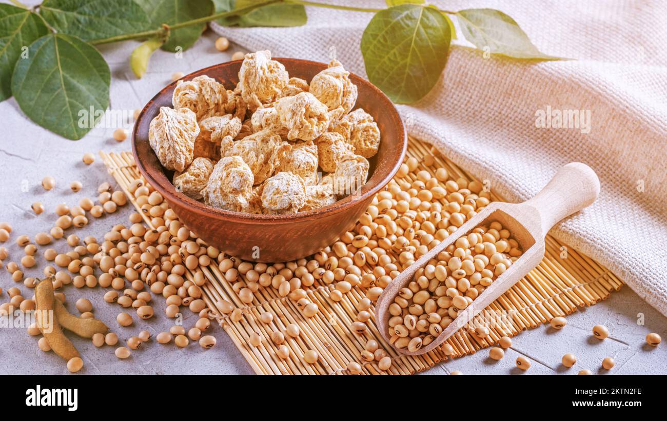 Pezzi di proteine di soia testurizzati (nutri nuggets), carne di soia cruda per vegani in recipiente di argilla su un tovagliolo di bambù sullo sfondo di burlap e ramo giovani Foto Stock