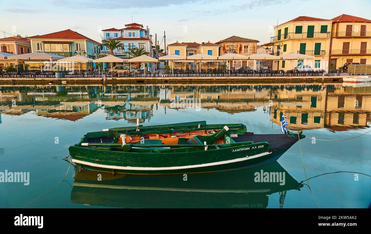 Luce del mattino, case sul lungomare, riflessi in acqua, barca verde, Lefkada città, capitale dell'isola, Lefkada isola, Lefkas, Ionian Isl Foto Stock