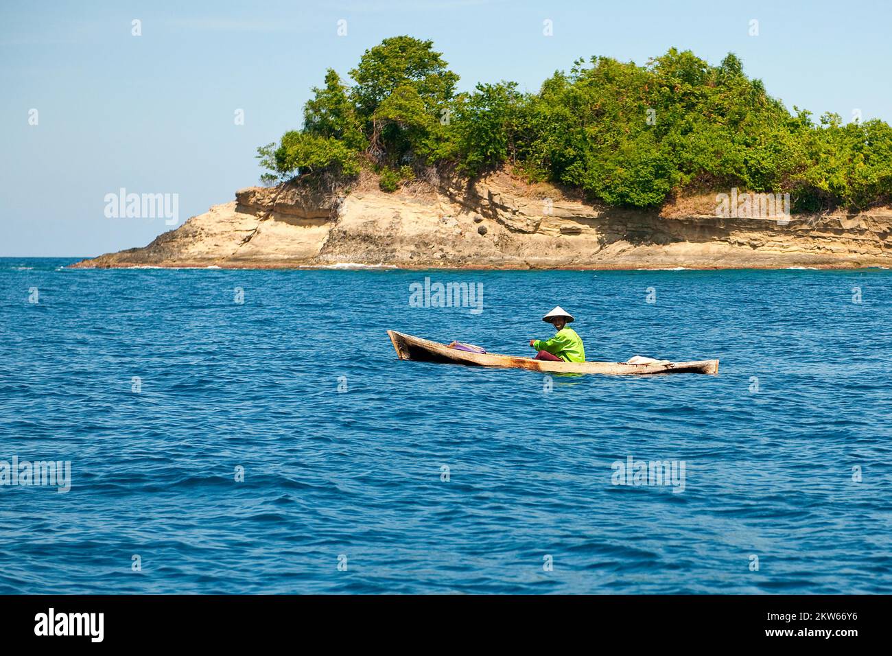 Pescatore in canoa canoe semplice barca sul mare ancora oceano Pacifico, sullo sfondo piccola isola, Isole Spezie, Molucche, Indonesia, Asia Foto Stock