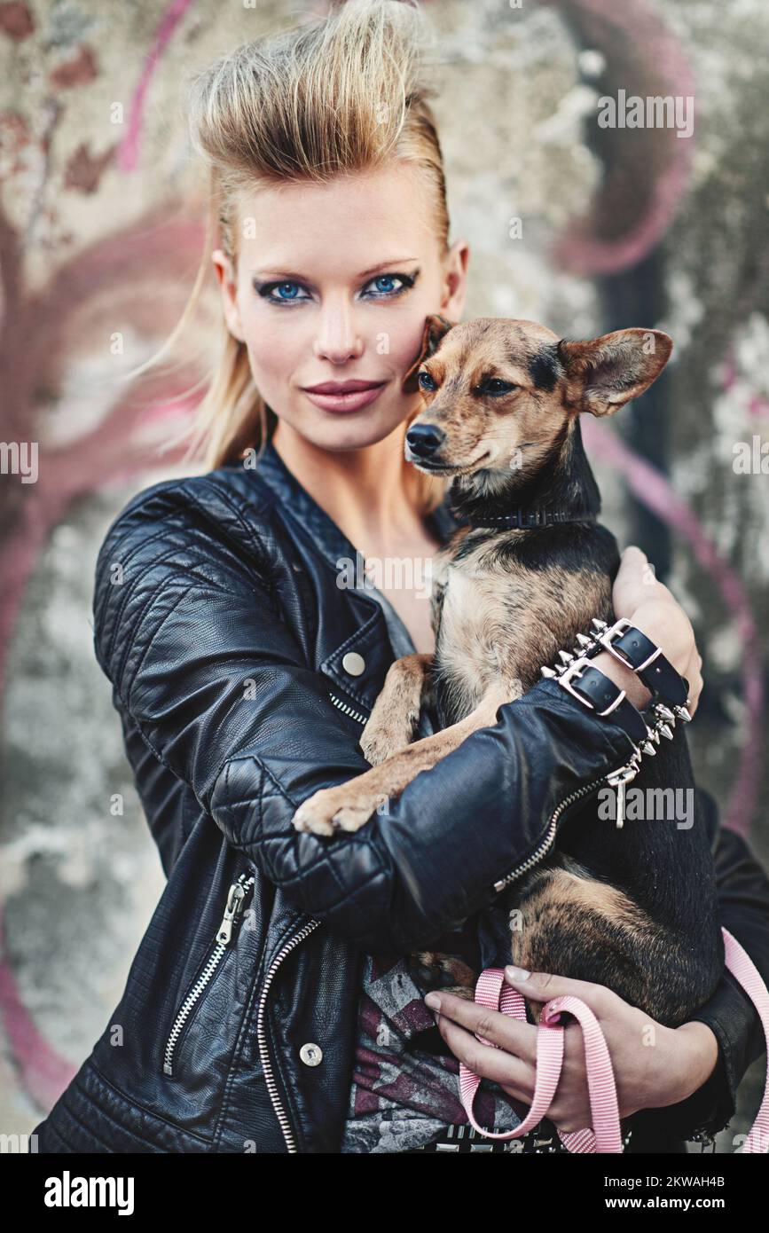 L'unico animale domestico per una rockstar come me. Ritratto corto di una giovane donna edgy che tiene il suo piccolo cane in un ambiente urbano. Foto Stock