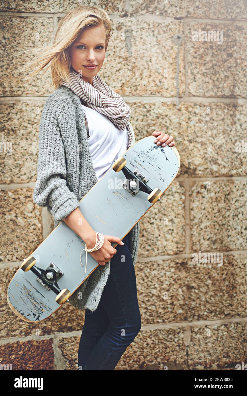 Non odiarmi perché non si può fuori-skate me. Ritratto corto di una giovane donna attraente che porta il suo skateboard contro una parete di mattoni. Foto Stock