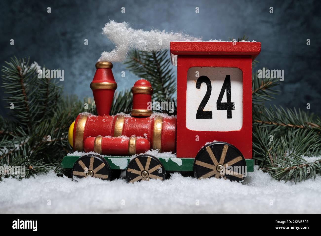 Giocattolo in legno del calendario dell'avvento del treno. Conto alla rovescia per la decorazione natalizia. Conto alla rovescia giorni fino a Natale. Composizione con rami d'albero sulla neve. Foto Stock