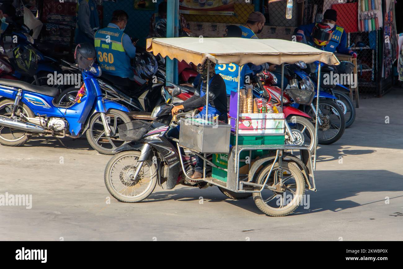SAMUT PRAKAN, THAILANDIA, ottobre 19 2022, un distributore di gelati guida una moto a tre ruote lungo una strada cittadina Foto Stock