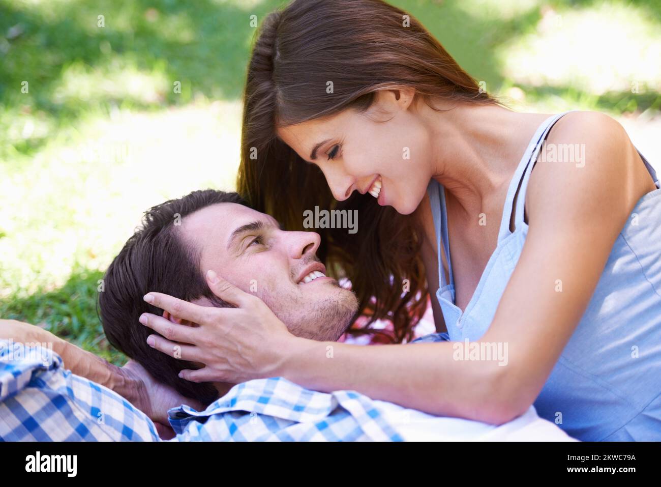 Giovane e così innamorato. Vista ritagliata di una giovane coppia sdraiata sull'erba del parco. Foto Stock