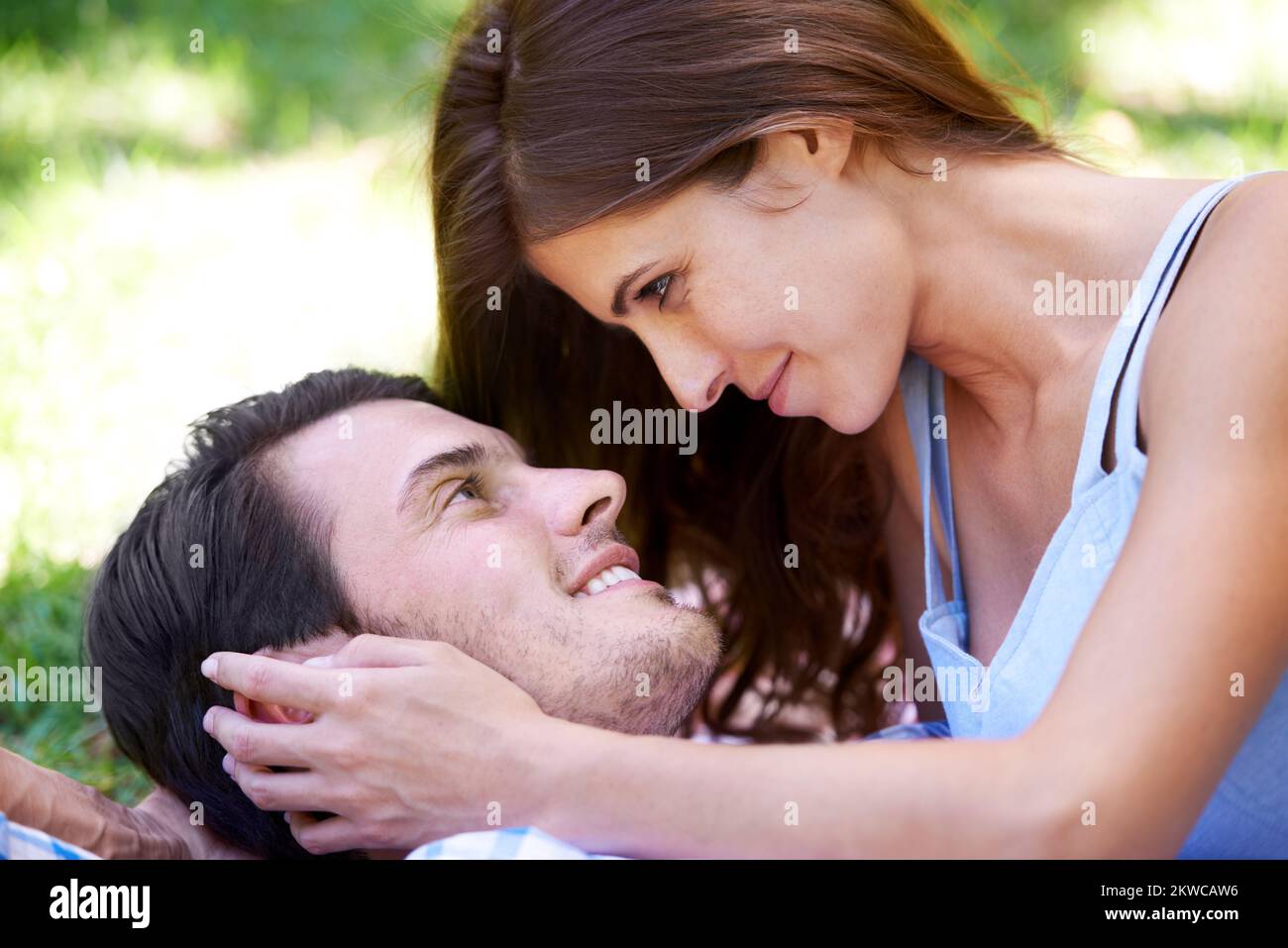 Amore primaverile. Vista ritagliata di una giovane coppia sdraiata sull'erba del parco. Foto Stock