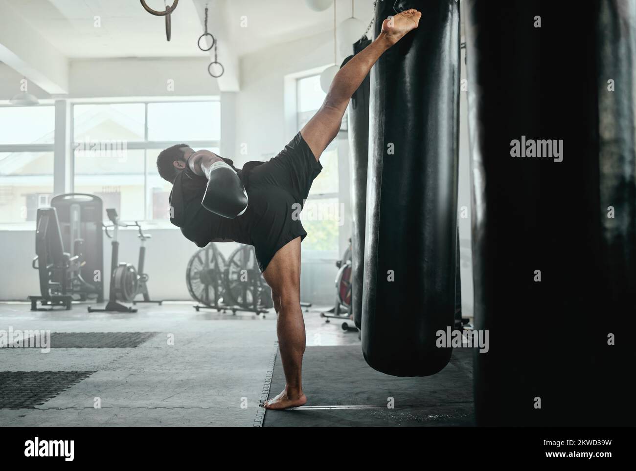 Allenamenti da combattimento maschile professionali, in forma e attivi con una borsa da punzonatura in palestra. kickboxer pratica, allenamento e fitness esercizio per la concorrenza Foto Stock