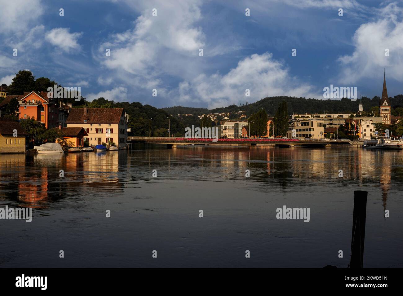 L'Hochrhein o l'Alto Reno a Schaffhausen, Svizzera settentrionale, attraversato da un moderno ponte stradale che collega Feuerthalen (a sinistra) all'Altstadt o al centro storico (a destra), con la torre romanica del 12th ° secolo e la guglia del Münsterkirche, Una volta la basilica di un'abbazia benedettina, ma ora un minster protestante o cattedrale. Foto Stock