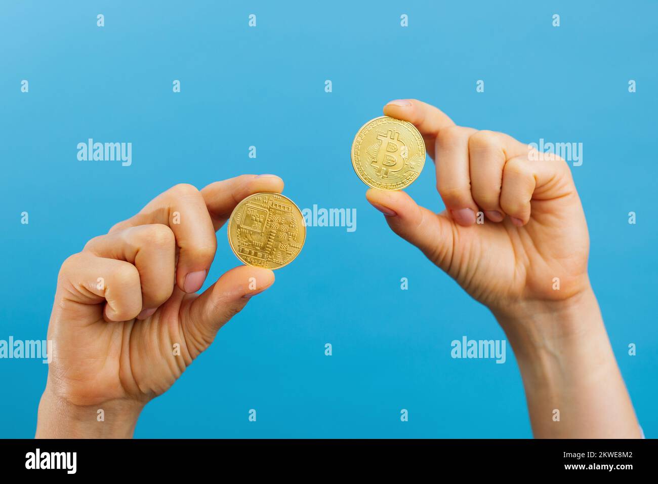 Primo piano di mani che tengono bitcoins d'oro, spazio di copia per la criptovaluta commerciale, moneta digitale, investimento elettronico. Studio interno ripresa isolata Foto Stock